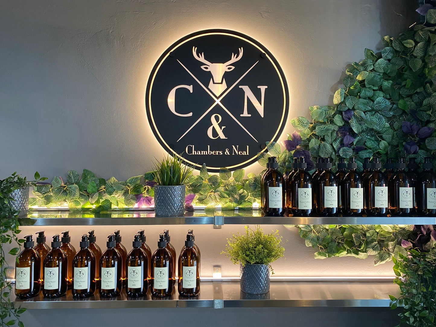 Bottles on an illuminated warm white shelf with a well lit 'Chambers & Neal' logo in the background. 24V 4mm COB LED strip lights within recessed silver micro profile used.