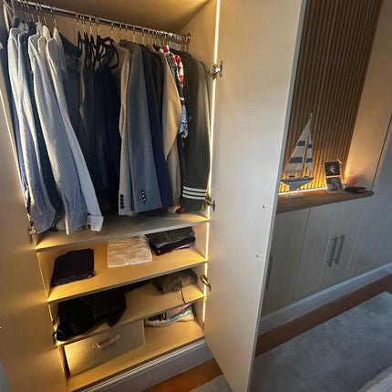 Open closet with hanging clothes and shelves, illuminated by warm 2700K integrated light lines. 4mm seamless COB LED strip lights used triggered on/off by 12V-24V double door sensors.