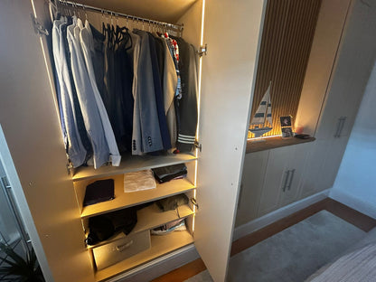 Open closet with hanging clothes and shelves, illuminated by warm 2700K integrated light lines. 4mm seamless COB LED strip lights used triggered on/off by 12V-24V double door sensors.