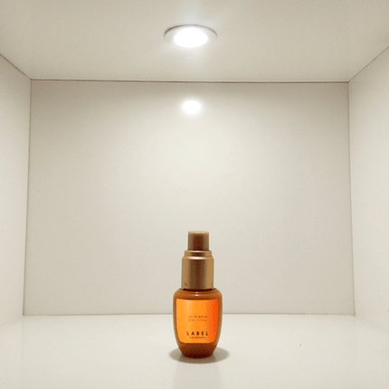 Recessed cabinet LED spotlight illuminating perfume bottle