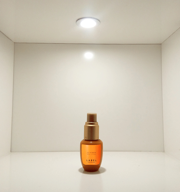 Recessed cabinet LED spotlight illuminating perfume bottle